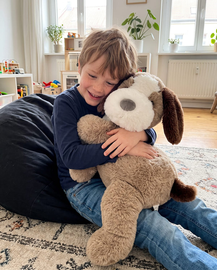 Junge drückt das Hunde-Gewichtskuscheltier im Wohnzimmer an sich